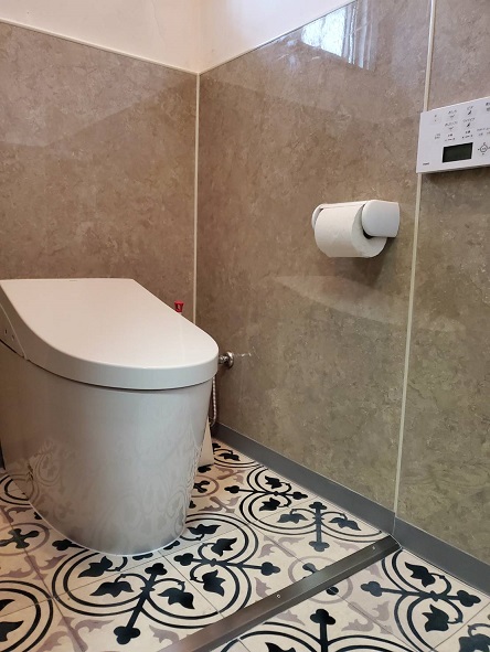 トイレの壁には重厚感がある落ち着いた色の セラール セレントを採用 金属調の建具やサインとコントラストのある仕上がりにOsaka Metro中央線 夢洲駅①セラール セレント CFN10296ZNサンドリバー ペール②セラール セレント CFN10301ZNクランチ