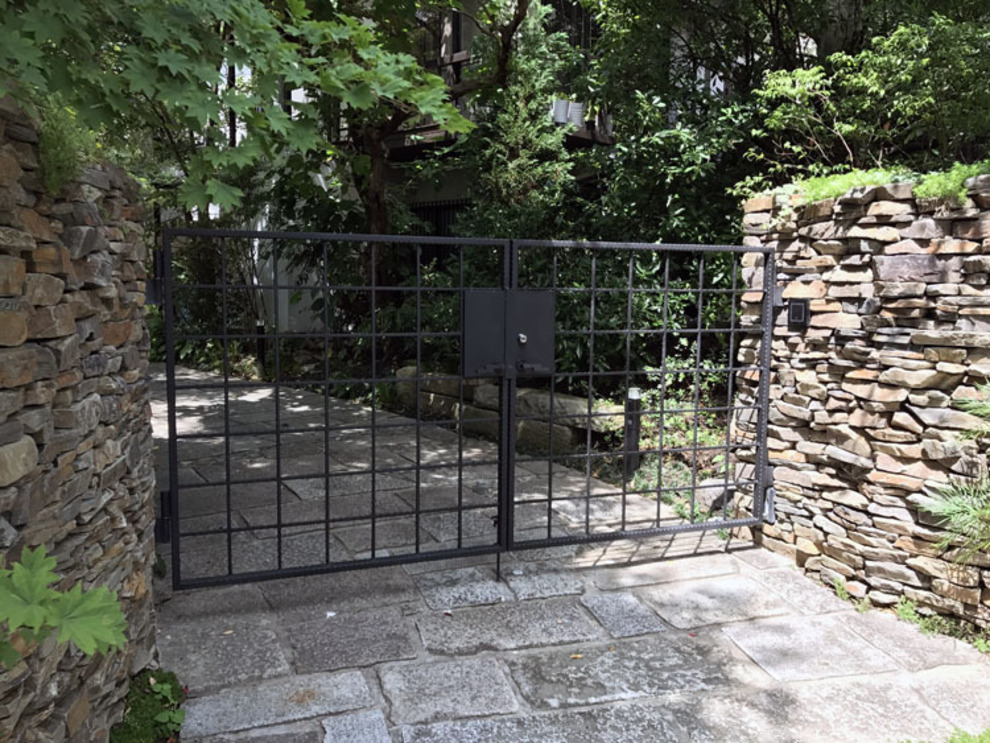 必要なものをすっきり組み込んだ、ロートアイアンの機能門柱付き両開き門扉。 格子をアレンジしたような、モダンだけれど落ち着いた風情に、心惹かれます。2枚目の写真は内側から撮影したもの。 表札やインターフォン、郵便受け、宅配ボックス、ライトなど、ご希望の