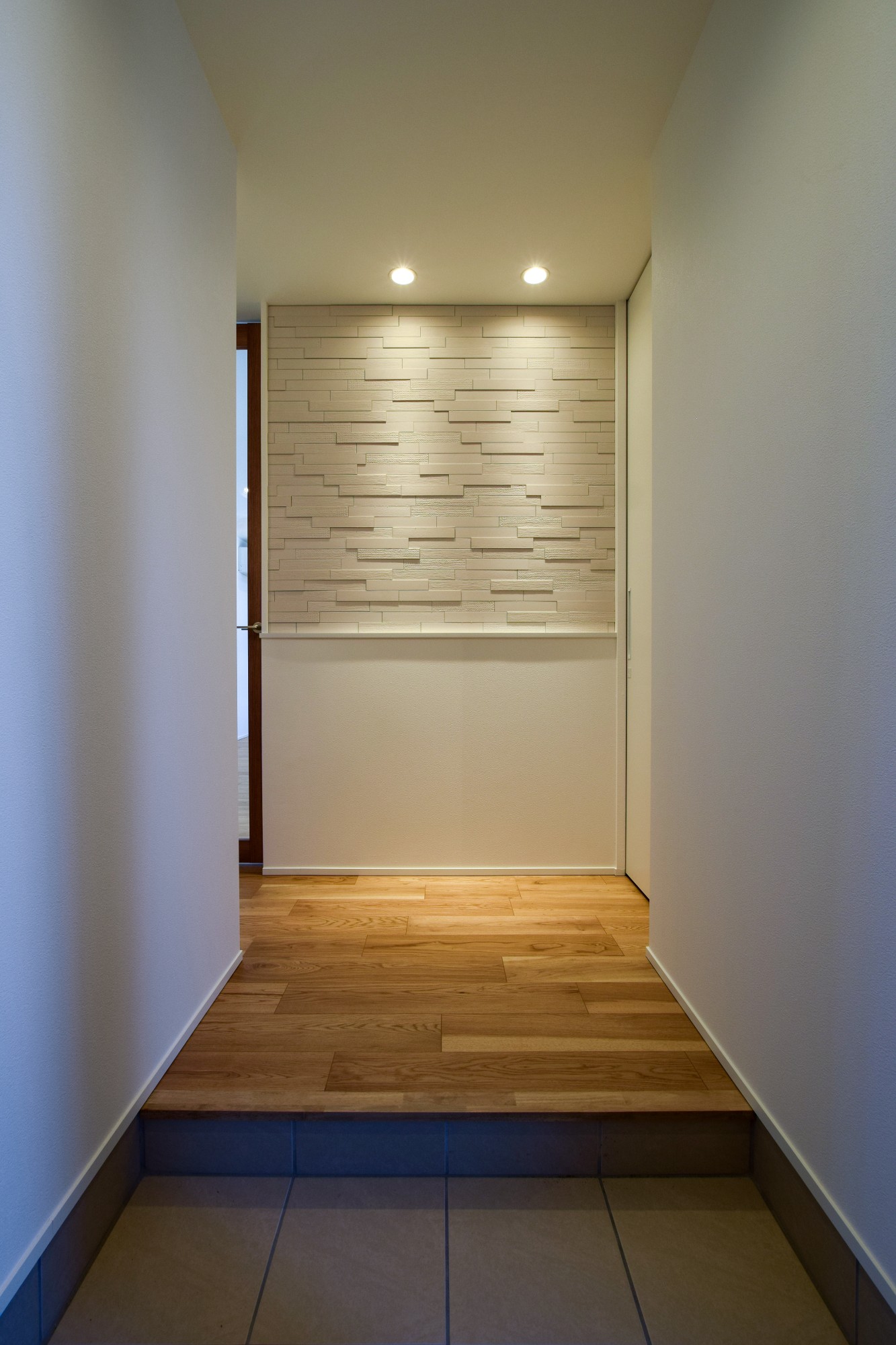 モダンで重厚感のある玄関ホール。正面の壁は外壁に使うタイル素材。収納も充実している くふうイエタテ