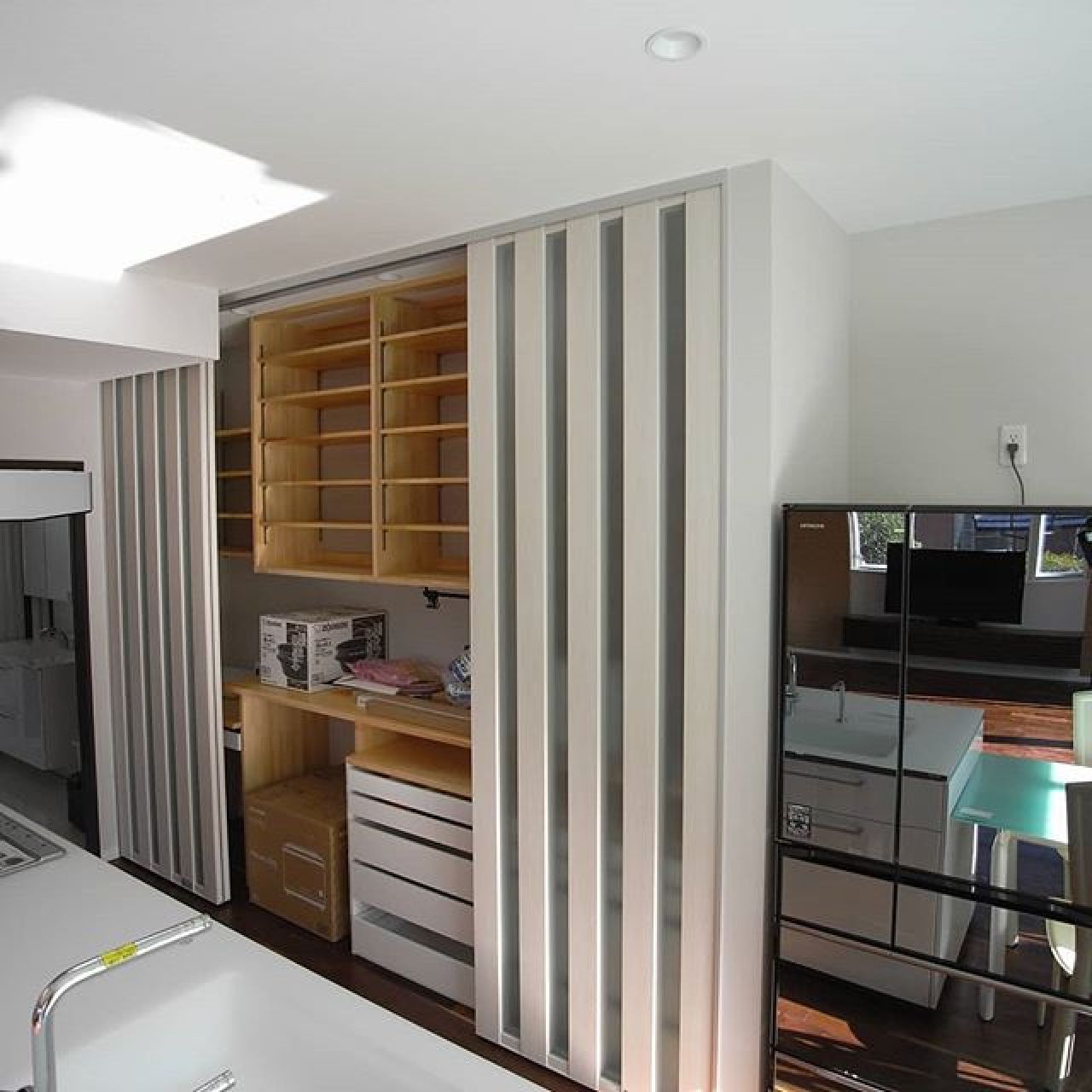 キッチンの造り付け食器棚兼システム収納。大工さんに棚を作ってもらい、正面に間仕切り用のスクリーンパーティションを設置する事で一体感を保ちかつ大容量の収納を実現。 スクリーンパーテーションキッチン造り付け家具食器棚収納注文住宅 - 高気密×高断熱×高