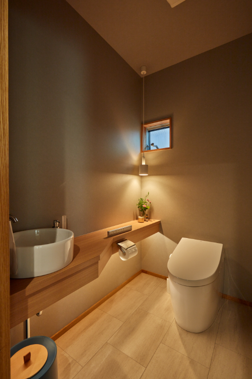 玄関から近い場所に配置したトイレ。照明器具とクロスの色を工夫して、シンプルな中にも上質なしつらえを表現した くふうイエタテ