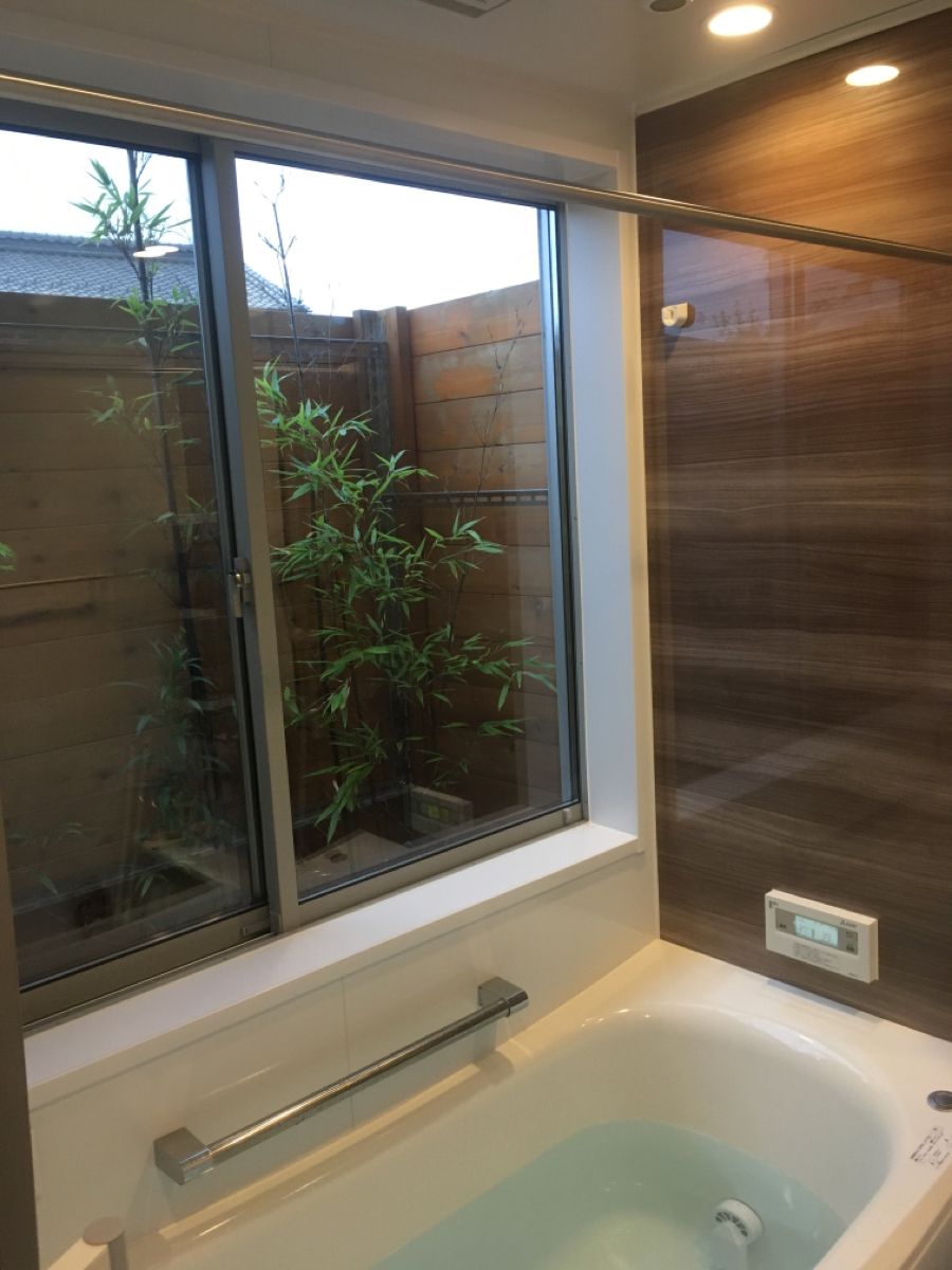 温泉宿のような和風半露天風呂の家 木目調の壁と御影石で仕上げたこだわりのお風呂。 庭への視線を考慮して浴槽は埋め込み式に。まるで旅館に行ったような安らぎを与えてくれます。四季の住まい_浴室