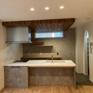 ベージュカラーで統一されたキッチンはインテリアの主役。白い下がり天井が空間のアクセントに。キッチンカウンターの下にスツールも置けそう。照明も